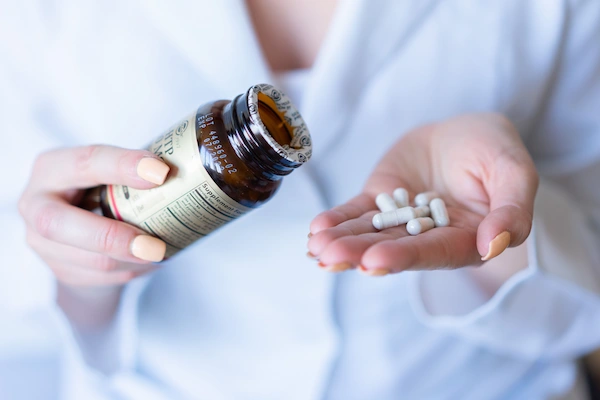 Imagen ilustrativa de unas manos sosteniendo una botella de medicina y pastillas.
